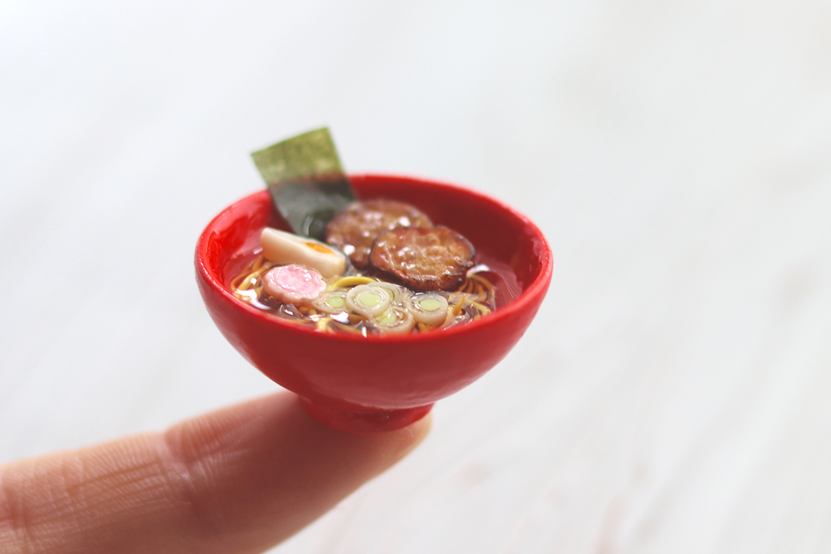 ラーメンのミニチュアフードを指先に乗せた写真