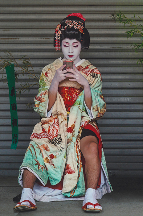 スマートフォンを見ながら座っている町娘の仮装をした男性