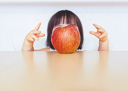 机の上のリンゴを念力で動かそうとしている子供