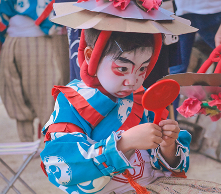 お祭りで化粧をした自分の顔を鏡で見ている子供