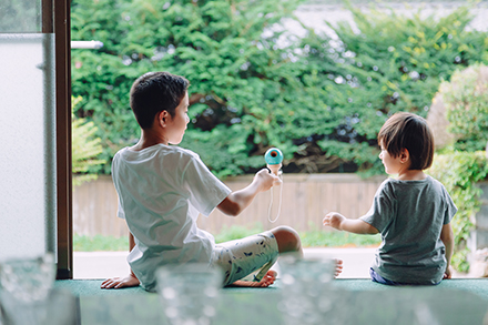 窓際で向かい合って遊んでいる2人の子供