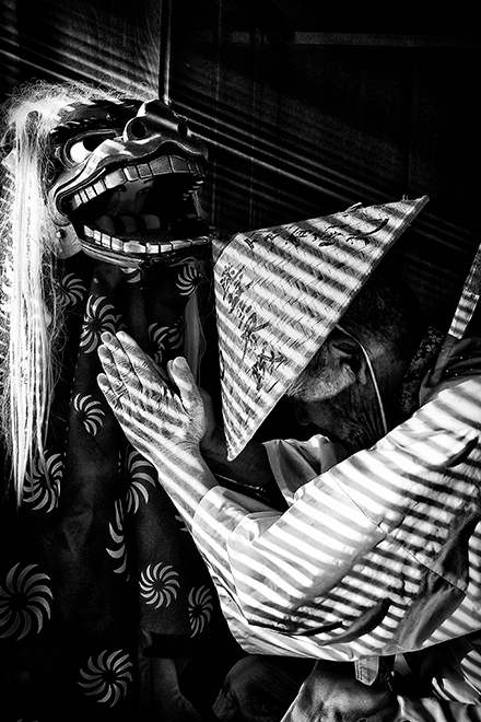 獅子舞に向かってお祈りしている老人