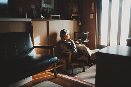 暖かそうなリビングでくつろぐ老人と猫