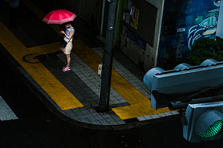 鮮やかな赤い傘を差す女性と信号機